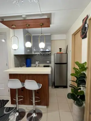 a kitchen with two bar stools and a refrigerator at 2BR DECA HOME Pasig City in Manila