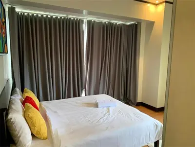 a bedroom with a white bed with pillows and a window at 2 Bedroom at The infinity Condominium at BGC in Manila