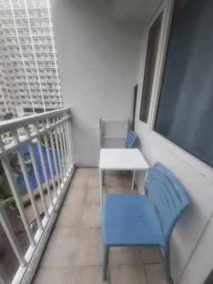 a balcony with a table and a blue chair at Amenity Pool View 1 BR balcony MOA SMX Ikea Shore002 in Manila