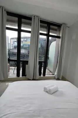 a bed with two towels on it in front of a window at STAYLUXIA BOUTIQUE HOTEL GRAMERCY Balcony FREE Pool, Gym, Netflix in Manila