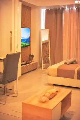 a bedroom with a bed and a table and a chair at Cozy Tahanan Azure Studio close to NAIA in Manila