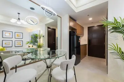 a dining room and kitchen with a glass table and chairs at Modern Condo at Park McKinley West with Wi-Fi and Washer in Manila