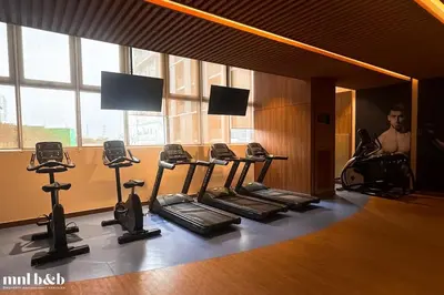 a gym with several tread machines and a man in a mirror at Modern Condo at Park McKinley West with Wi-Fi and Washer in Manila