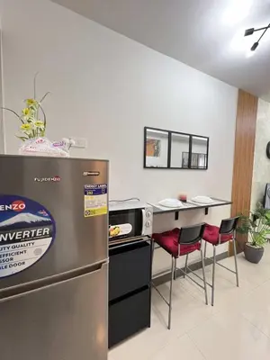 a kitchen with a refrigerator and a counter with red chairs at Chic Urban Escape at S Residence Tower 3 in Manila