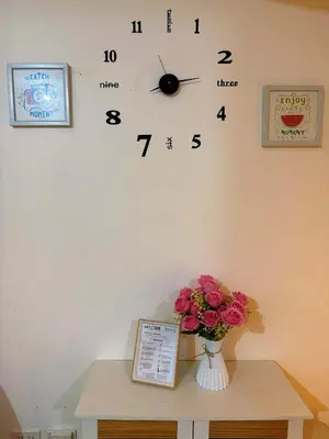 a clock on a wall with a vase of flowers at The Warm Suite By ANC at Azure in Manila