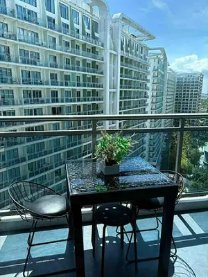 a table and chairs on a balcony with a building at The Warm Suite By ANC at Azure in Manila