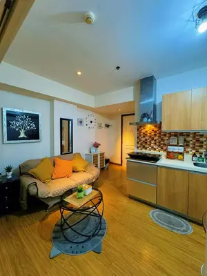a living room with a couch and a kitchen at The Warm Suite By ANC at Azure in Manila