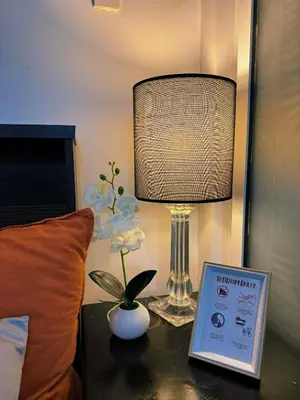 a lamp sitting on a table next to a bed at The Warm Suite By ANC at Azure in Manila