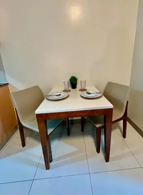 a table and two chairs with plates and glasses on it at 1BR at One Uptown Residence BGC Across Uptown Mall in Manila