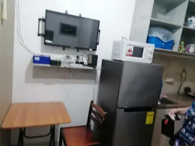 a kitchen with a refrigerator and a table and a tv at Aureascondo in Manila