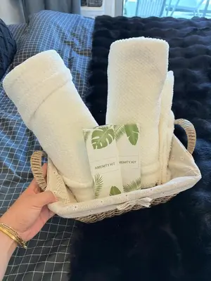 a person holding a tray with towels on a bed at Ohana JPL Azure Staycation in Manila