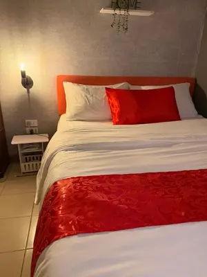 a bed with an orange headboard and red pillows at PaulBert's Cabins III in Manila