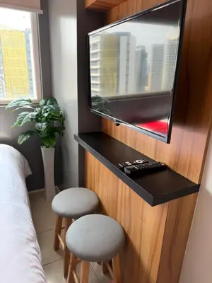 a bedroom with a flat screen tv and two stools at PaulBert's Cabins III in Manila