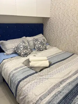 a bed with a blue headboard and pillows on it at Spacious 2BR in Shore3 in Manila