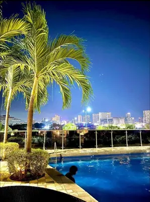 a palm tree and a swimming pool with a city skyline at Shore 2 Residence Erlinda suite in Manila