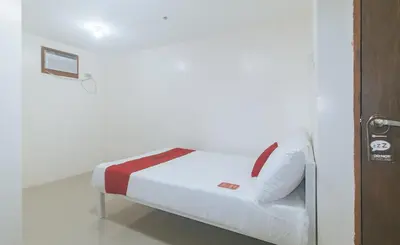 a small bed in a room with a door at RedDoorz at FCCG GoldMoon Boutique Hotel in Manila