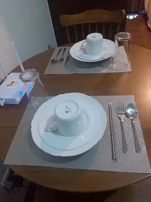 a wooden table with two white plates and silverware at Budget-Friendly Condo in Makati in Manila