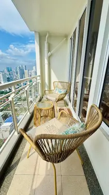 three chairs on a balcony with a view of the city at Brand New Cozy 2 BR unit in Pasig in Manila