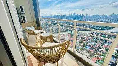 a balcony with two chairs and a view of a city at Brand New Cozy 2 BR unit in Pasig in Manila