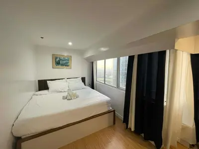 a bedroom with a white bed with a window at Luxury 2BR with Stunning Skyline Views in BGC in Manila