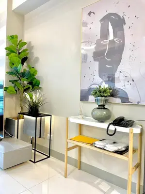 a room with a table and a shelf with flowers at Uptown Parksuites - Elegant 2 Bedroom Unit with Balcony in BGC in Manila