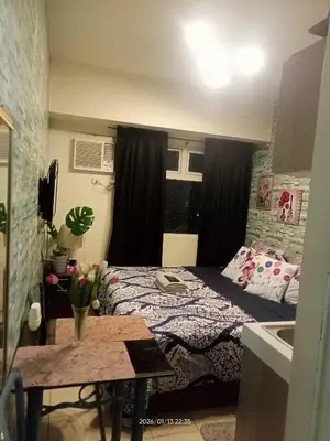 a bedroom with a bed and a table and a window at Urban Deca Tower at Mandaluyong in Manila