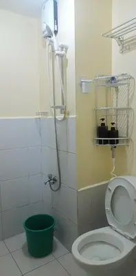 a bathroom with a shower with a toilet and a bucket at Urban Deca Tower at Mandaluyong in Manila