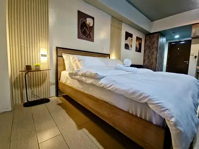 a bedroom with a large bed with white sheets at Luxe Spacious Cozy Venice BGC 65inTV Surround Sound in Manila