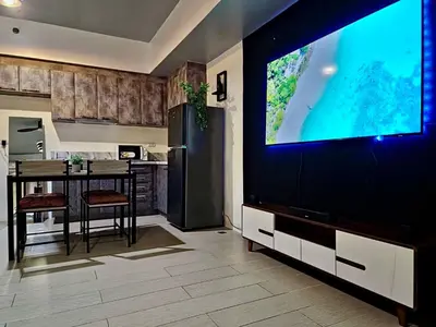a kitchen with a dining table and a large screen television at Luxe Spacious Cozy Venice BGC 65inTV Surround Sound in Manila