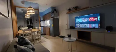 a living room and kitchen with a large screen television at Avida Sucat Paranaque City in Manila