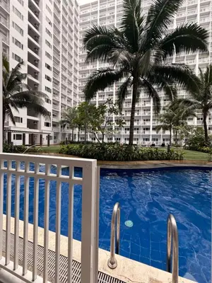 a swimming pool with palm trees and buildings at Direct Access to pool GK Suite in Manila