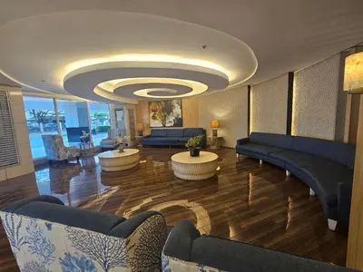 a living room with couches and tables in a building at Cozy 1BR Balcony Pool View with WiFi & Netflix near MOA and NAIA Airport in Manila