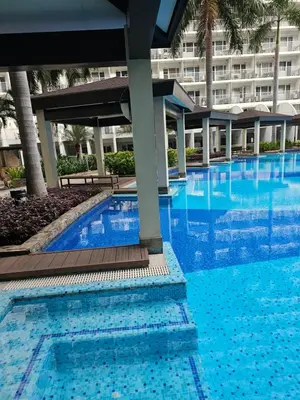 a large swimming pool with a large building in the background at Cozy 1BR Balcony Pool View with WiFi & Netflix near MOA and NAIA Airport in Manila