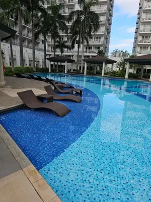 a large swimming pool with chairs in a building at Cozy 1BR Balcony Pool View with WiFi & Netflix near MOA and NAIA Airport in Manila