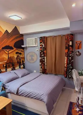a bedroom with two beds and a painting on the wall at Cozy African Home in Parañaque in Manila