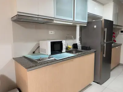 a kitchen with a microwave and a sink and a refrigerator at BGC Luxe Condo I Facing Grand Hyatt & Uptown Mall in Manila
