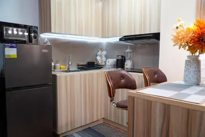 a kitchen with a refrigerator and a table with chairs at Cozy Staycation in The Radiance Manila Bay in Manila