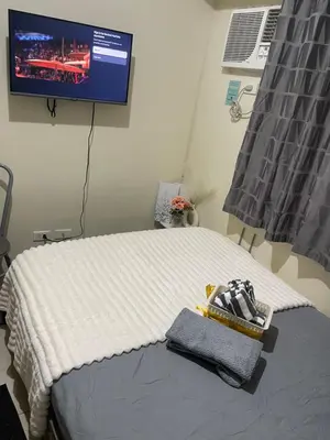 a bedroom with a bed with a tv on the wall at Haven Suites by Amf in Manila