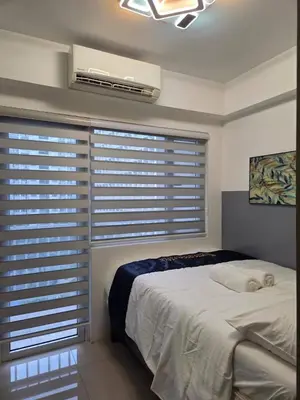 a bedroom with a bed and a window with blinds at Shore 1 Residences in Manila