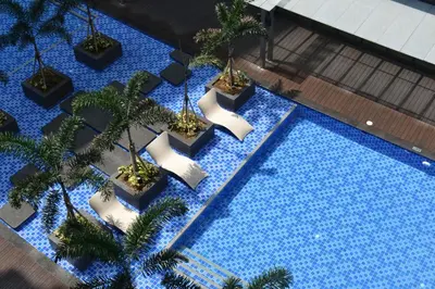an overhead view of a swimming pool with palm trees at Cozy Gentry Manor TV Netflix Seaview near Okada MOA17V in Manila
