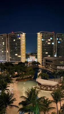 a city at night with tall buildings and palm trees at Azure Urban Resort Residences in Manila