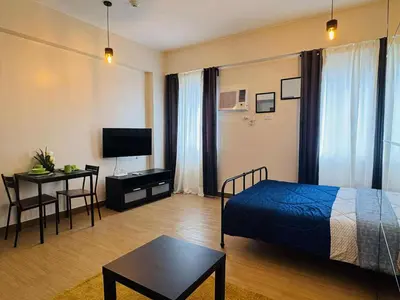 a bedroom with a bed and a table and a television at Beirut Bliss Suite at Hope Residences Trece Martires in Trece Martires