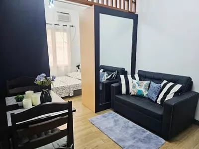 a living room with a black couch and a mirror at Paseo Verde Las Pinas - Sleeps 2 Adults 2 Children in Manila