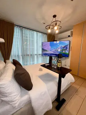 a hotel room with a bed with a television on it at One uptown Residence,BGC, Manila 1bedroom in Manila
