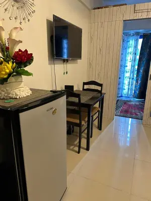 a kitchen and dining room with a table and a tv at Sea Residences Elegant Place by Paul in Manila