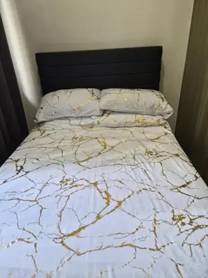 a bed with a blue and gold comforter and pillows at ZEN 2 SHORE RESIDENCES Tower A in Manila