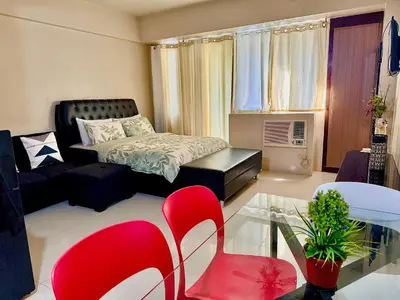 a living room with a bed and red chairs at Apartment near Airport at One Palm Tree Villas in Manila