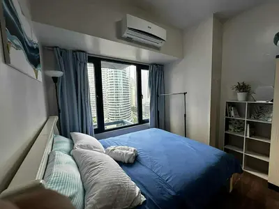 a bedroom with a blue bed and a window at AIR RESIDENCES MAKATI Staycation in Manila