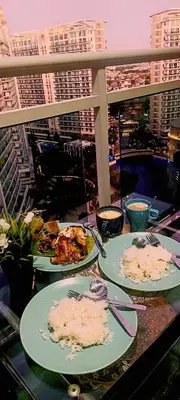 a table with plates of food on a balcony at AZURE RESIDENCES near International AIRPORT MANILA in Manila