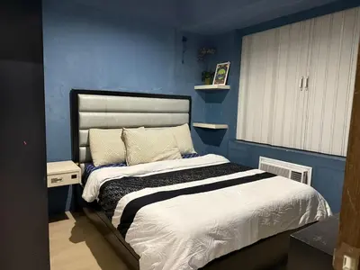 a bedroom with a bed with a blue wall at 1 Bedroom Apartment Across NAIA T3 in Manila